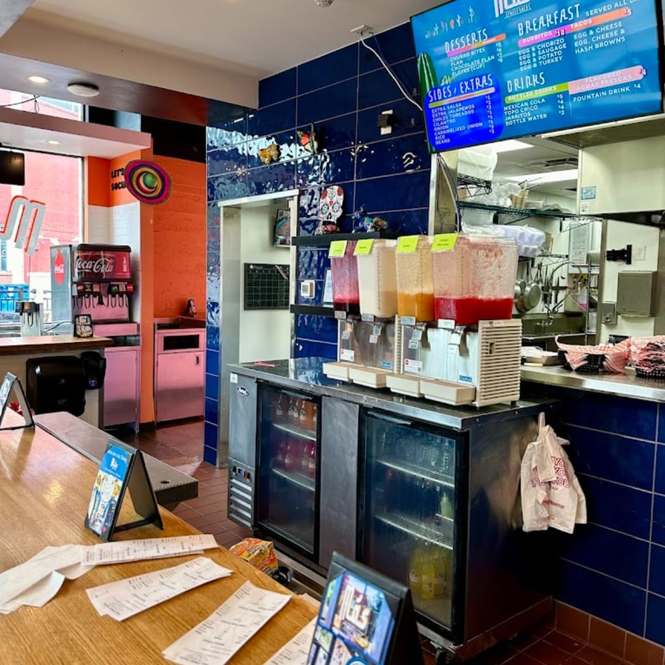 Interior of Mas Street Tacos with a counter, drink dispensers, menu board, and soda fountain.